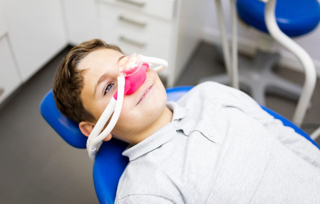 Young child in dental chair receiving fluoride treatment at pediatric dental office.