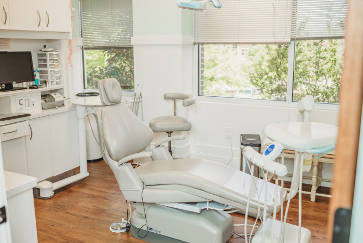 Bright pediatric dental operatory with chair, modern equipment, and colorful storage bins for children's comfort.